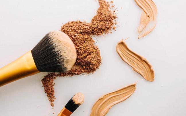 Una brocha y un pincel con maquillaje en crema y en polvo.