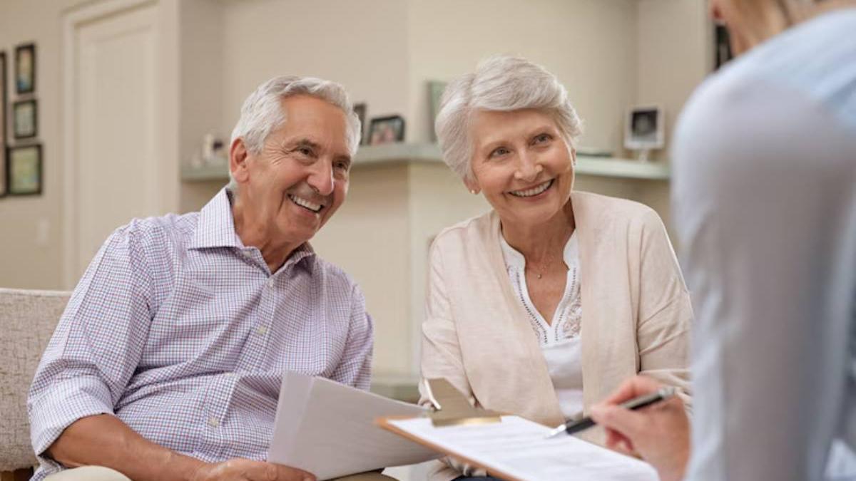 Pareja de personas mayores sonríen en una conversación con su asesora financiera.