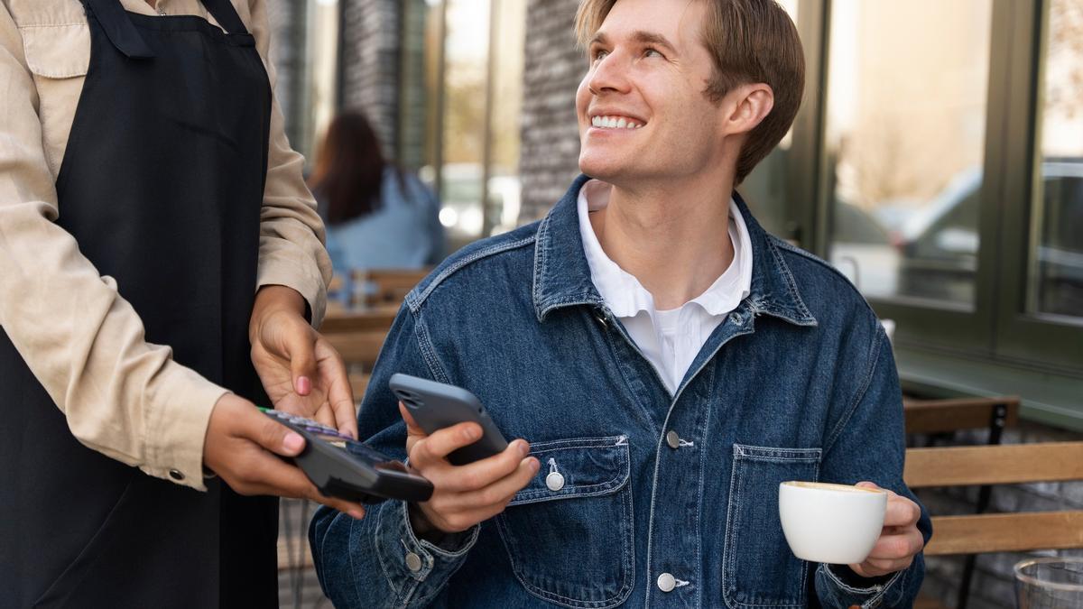 Un hombre paga un café con el teléfono móvil.