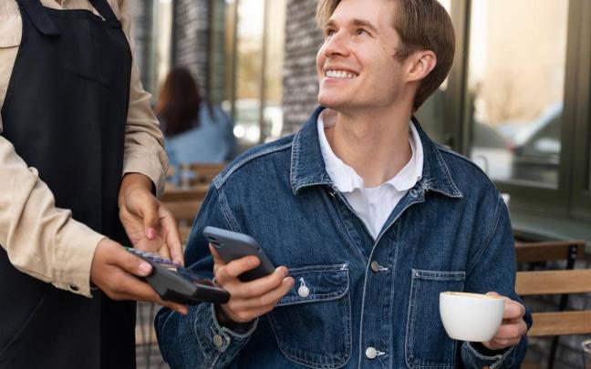 Un hombre paga un café con el teléfono móvil. Un hombre paga un café con el teléfono móvil.