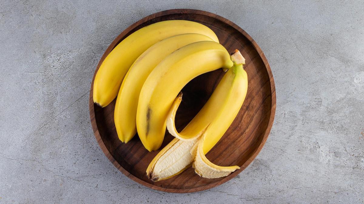Plátanos amarillos colocados sobre un plato de madera.