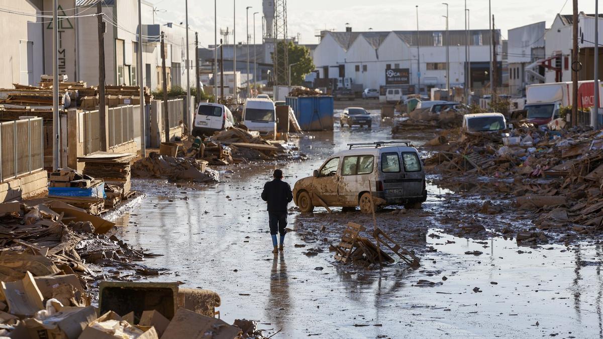 Una persona camina por una calle del polígono de Catarroja tras el paso de la riada causada por la dana del pasado mes de octubre.