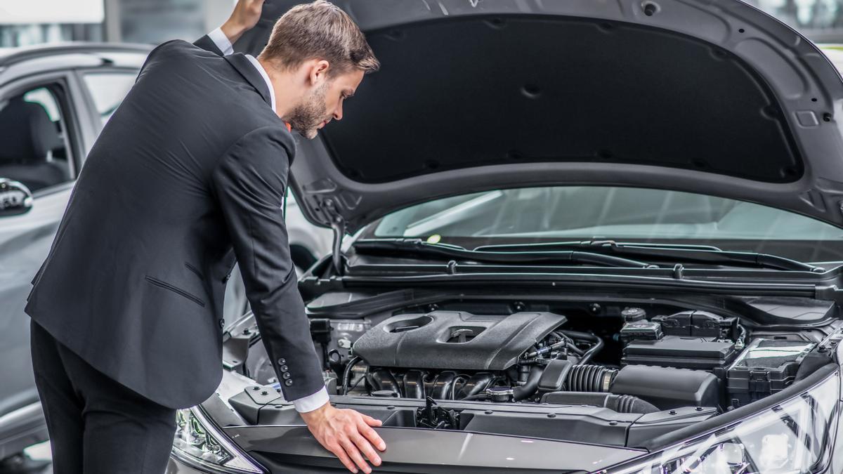Un hombre inspecciona el motor de un coche.