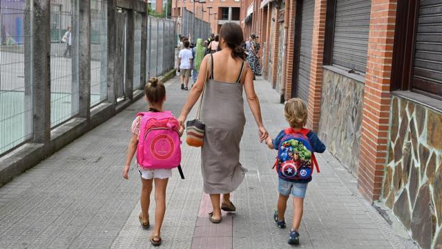 Una mujer lleva a sus hijos al colegio.