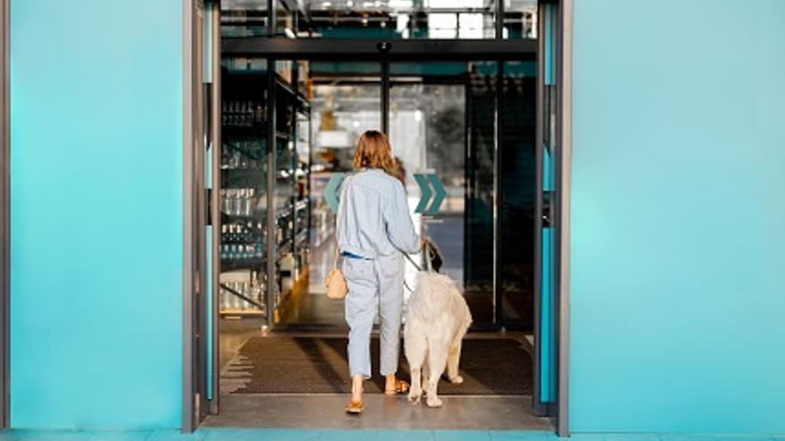 Una mujer entra con su perro en un supermercado.