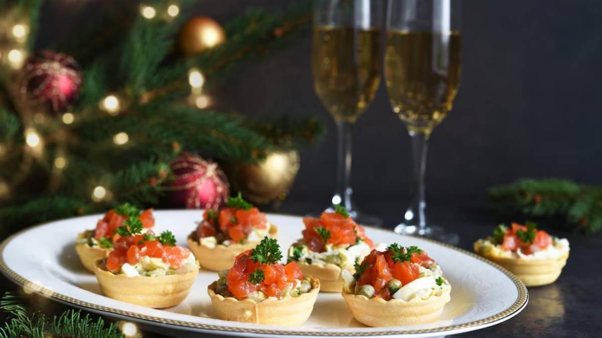 Pintxos con dos copas de champán de fondo y un árbol de Navidad