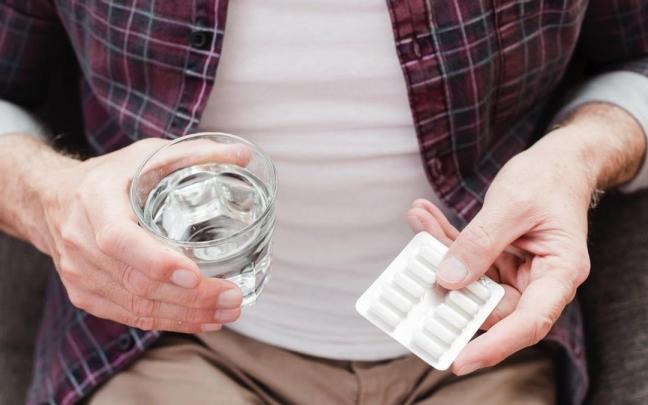 Un hombre toma un analgésico de los que no faltan en cualquier botiquín.