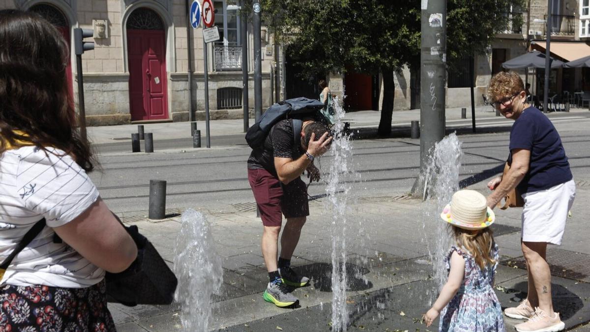 Varias personas se refrescan en una fuente.