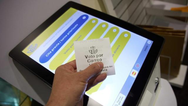 Una persona con un ticket de voto por correo en una oficina de Correos.