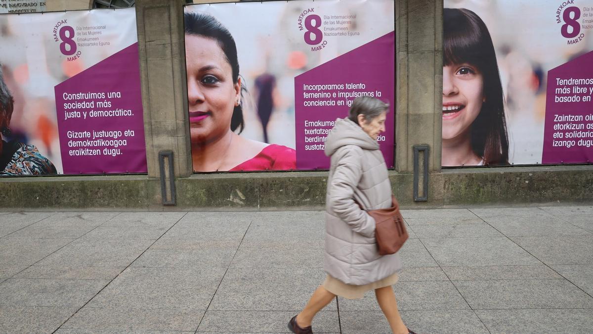 Una mujer camina frente a los carteles del 8M colocados en el Palacio de Navarra.