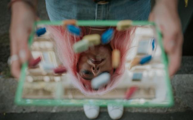 Una joven sostiene una bandeja con varias pastillas.