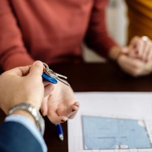 Un agente inmobiliario entrega las llaves de una vivienda a una pareja.