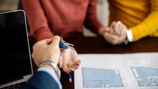 Un agente inmobiliario entrega las llaves de una vivienda a una pareja.