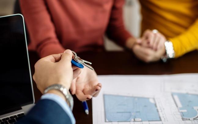 Un agente inmobiliario entrega las llaves de una vivienda a una pareja.