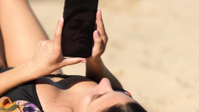 Mujer usa el móvil en la playa