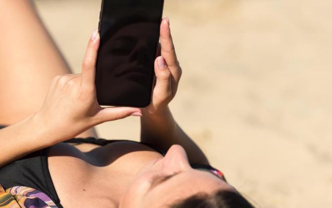 Mujer usa el móvil en la playa