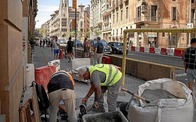 Dos trabajadores en plena tarea en una calle de Barcelona.