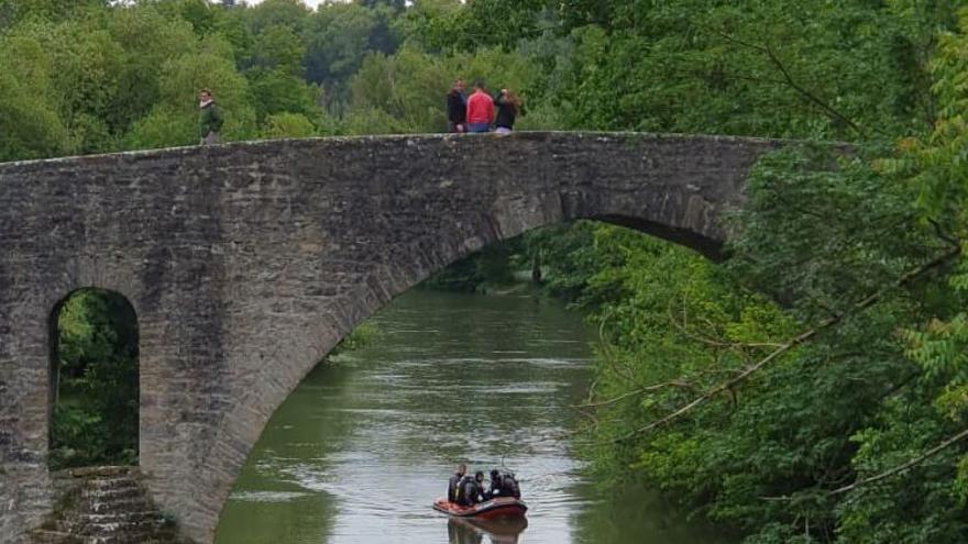 Bomberos recorren el río en una embarcación.