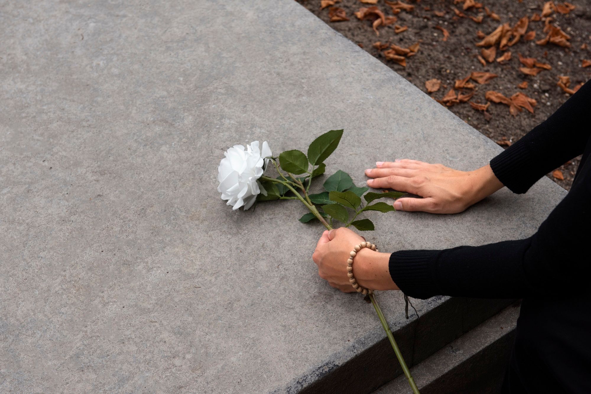 Una mujer deposita una flor en una tumba.