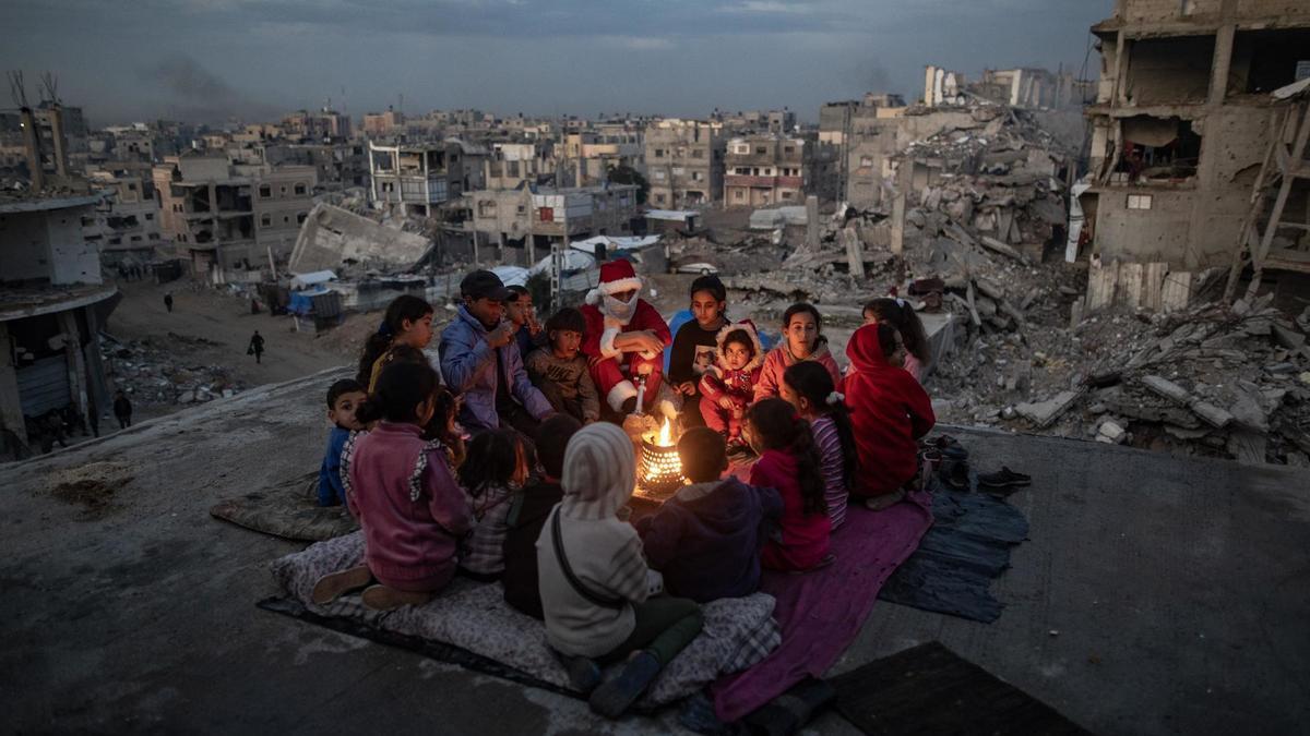 Un desplazado palestino vestido como Papa Noel, rodeado de niños palestinos