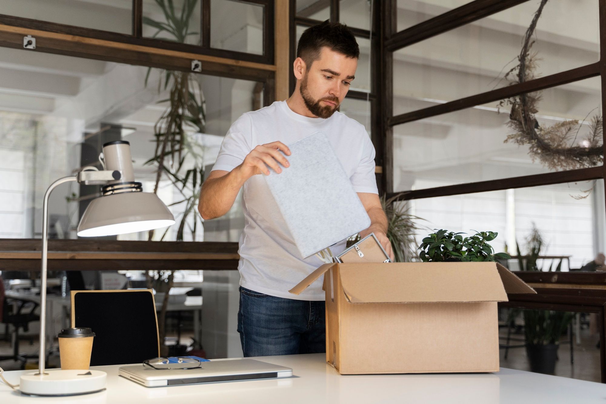 Un hombre recoge las cosas de su escritorio para cambiar de puesto.