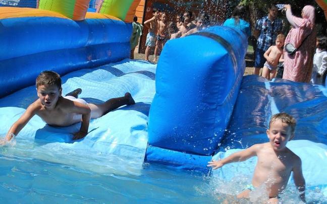 Un grupo de niños se divierte con unos hinchables acuáticos en una piscina.