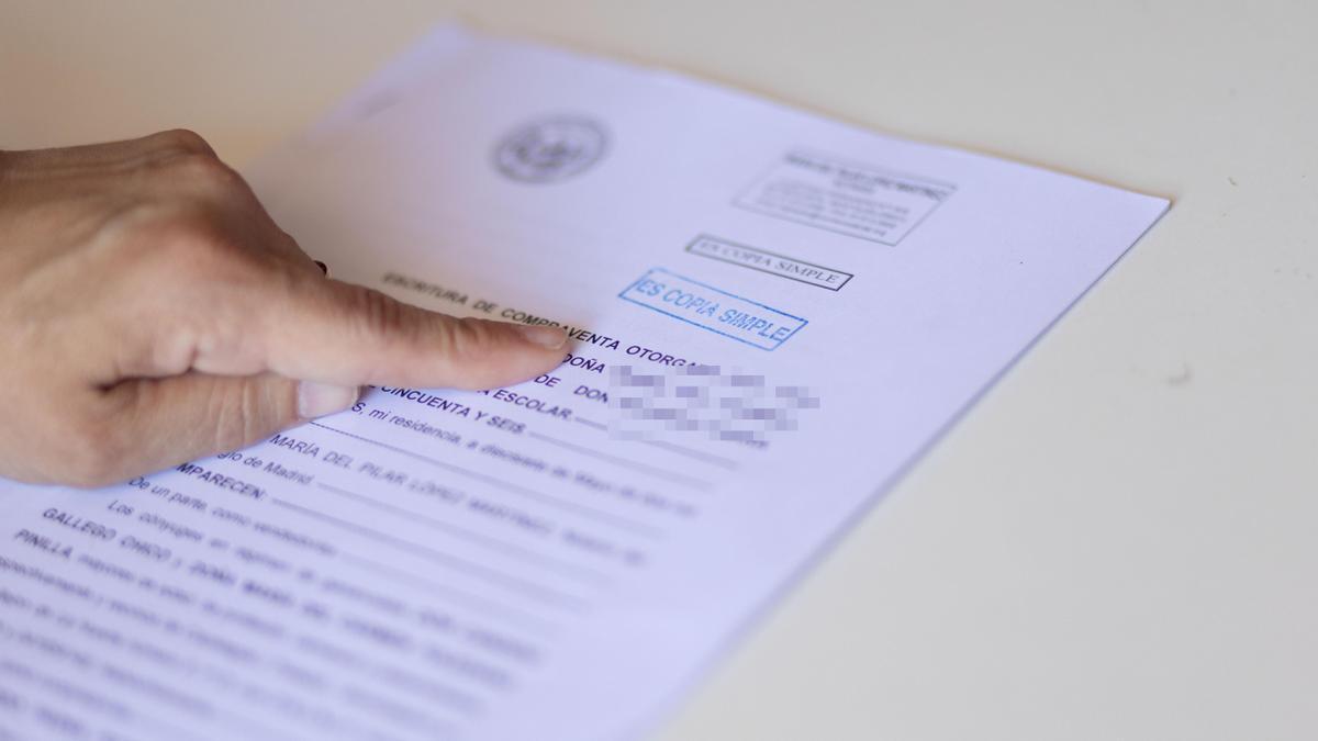 Una persona lee la escritura de compraventa de una hipoteca.