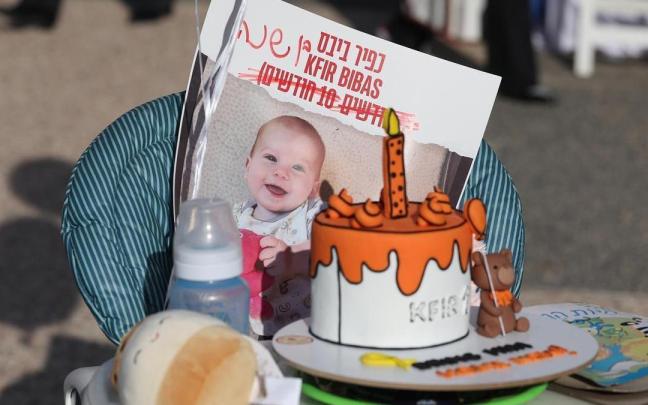Una silla de bebé es decorada con un pastel y una foto de Kfir en un acto en Tel Aviv.