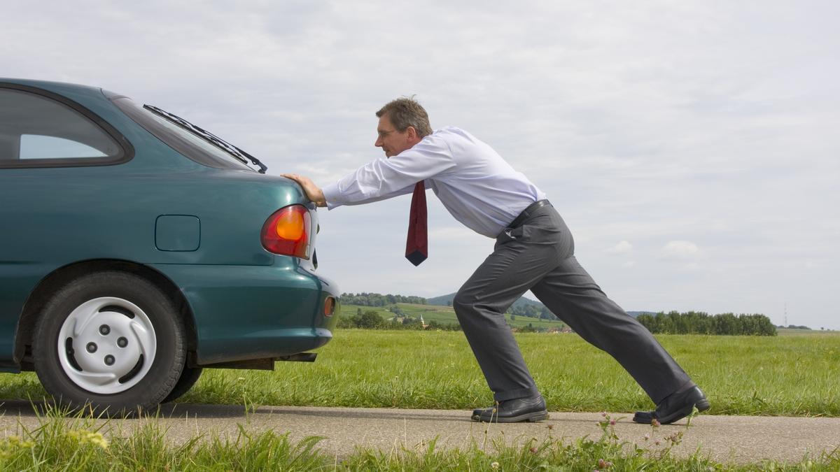 Un hombre empuja un coche para intentar que arranque.