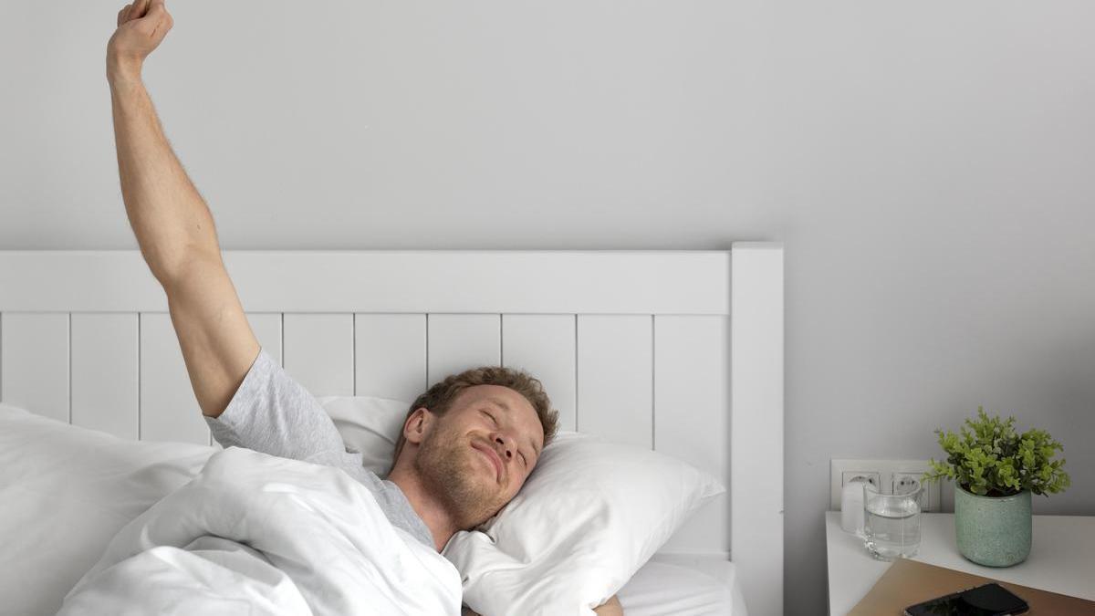 Hombre se despierta feliz después de haber dormido plácidamente toda la noche.