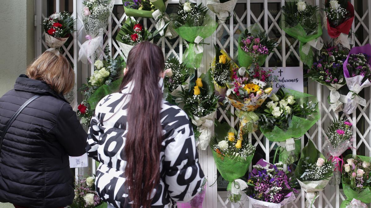 Dos personas delante de la tienda donde trabajaba una mujer de 42 años hallada muerta en su vivienda, a 29 de noviembre de 2022, en Lugo.