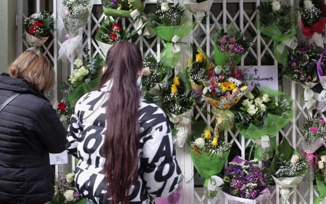 Dos personas delante de la tienda donde trabajaba una mujer de 42 años hallada muerta en su vivienda, a 29 de noviembre de 2022, en Lugo.