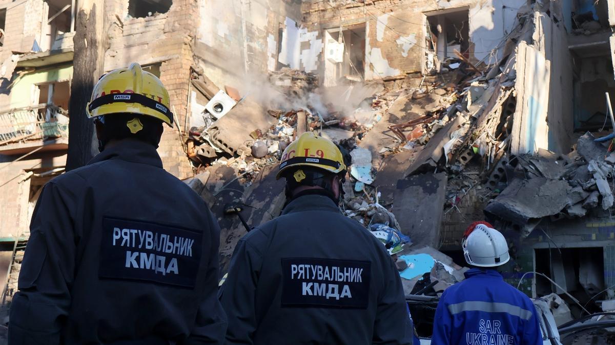 Bomberos de Ucrania frente a un edificio destruido por un bombardeo ruso.