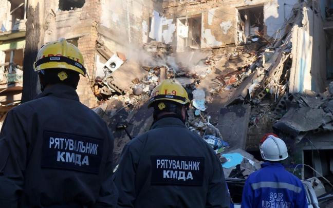 Bomberos de Ucrania frente a un edificio destruido por un bombardeo ruso.