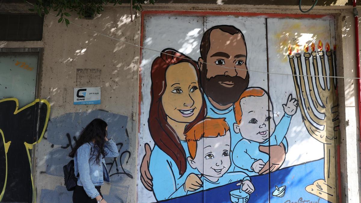 Una mujer pasea ante un grafiti de la familia Bibas en Tel Aviv.