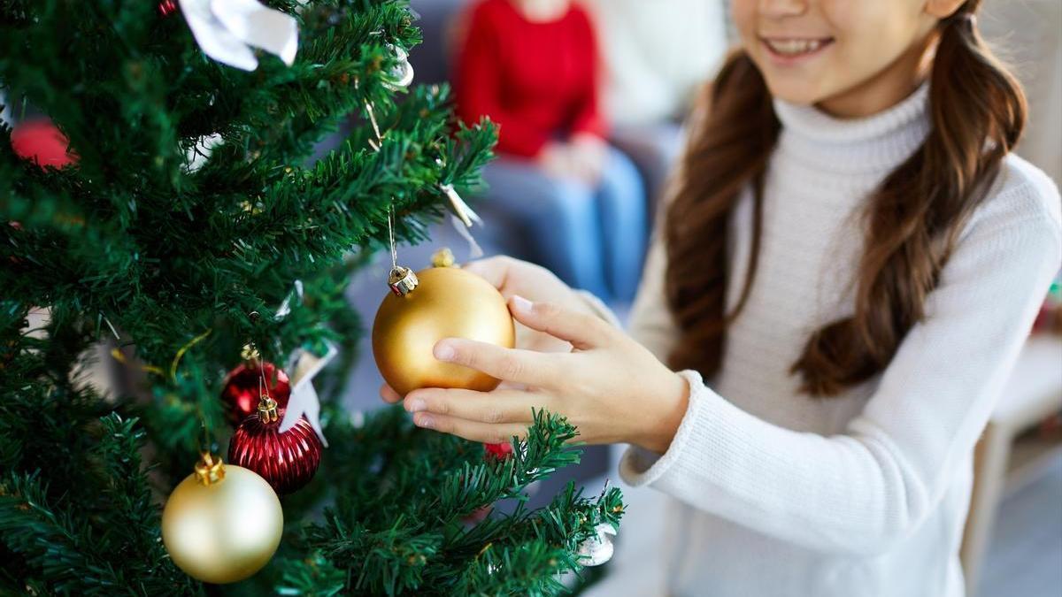 Niña adornando el árbol de Navidad