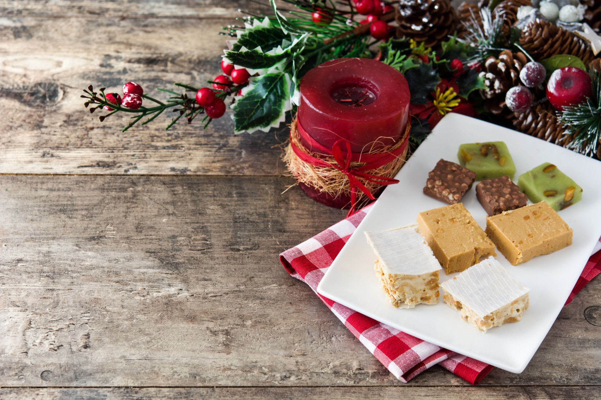 Distintas variedades de turrón sobre una mesa con decoración navideña.