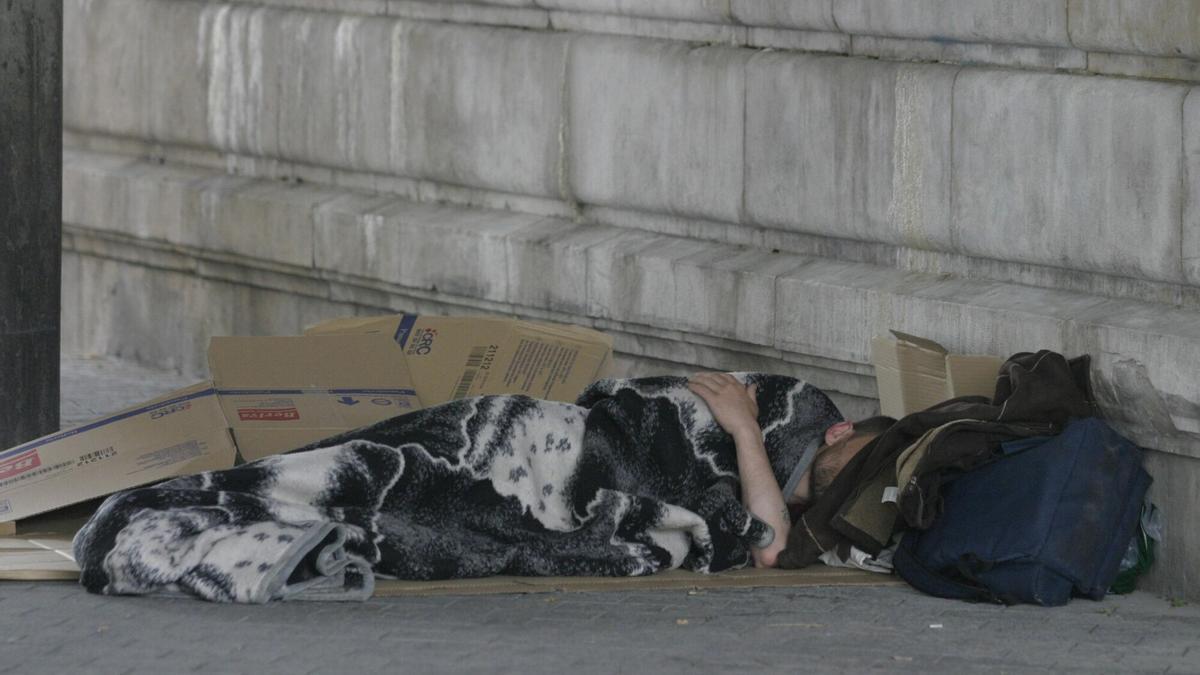 Una persona sin hogar se protege del frío en una calle de Bilbao.