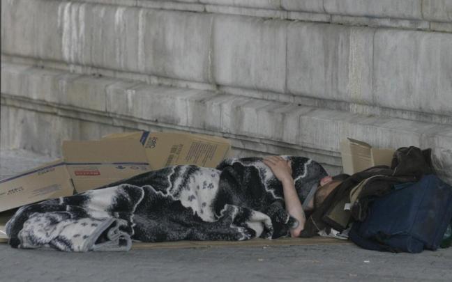 Una persona sin hogar se protege del frío en una calle de Bilbao.