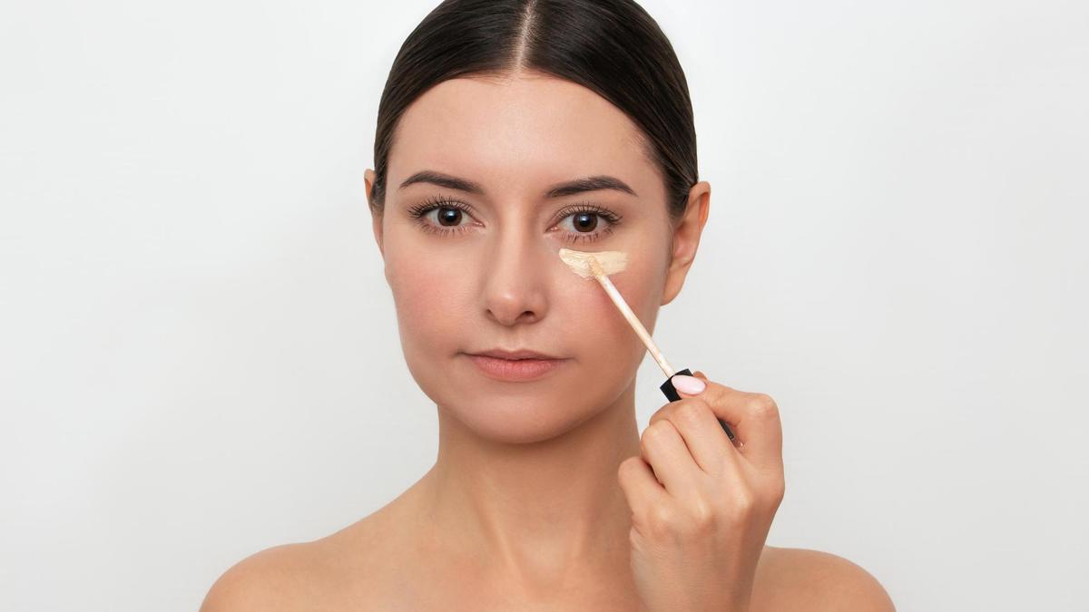 Una mujer se aplica corrector en las ojeras.