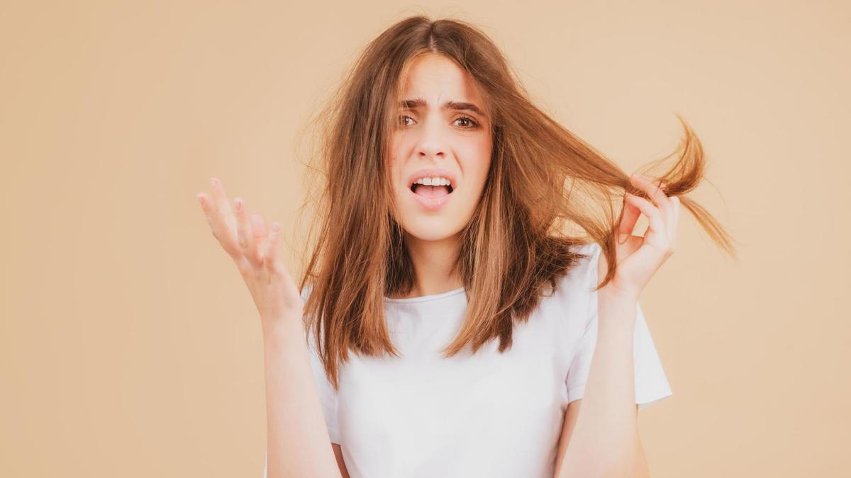 Una mujer enfadada por el encrespamiento de su pelo.