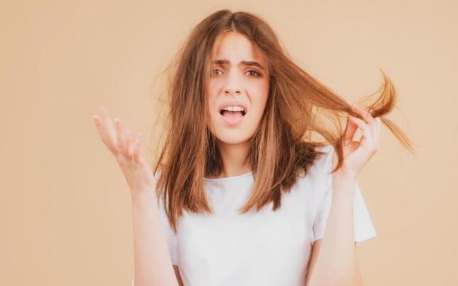 Una mujer enfadada por el encrespamiento de su pelo.