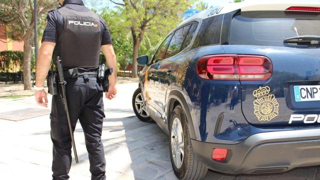 Un agente de la Policía Nacional junto a su vehículo.