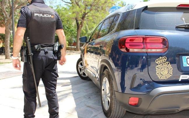 Un agente de la Policía Nacional junto a su vehículo.