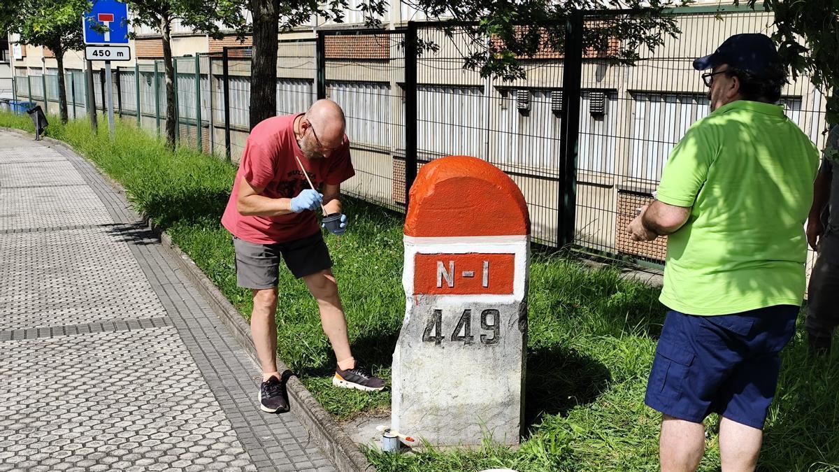 Dos miembros de Burdina pintando un mojón.