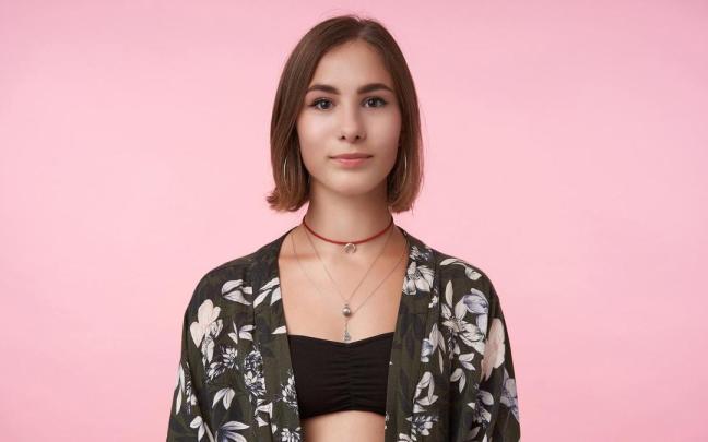 Una joven luce un choker rojo junto a otras cadenas.