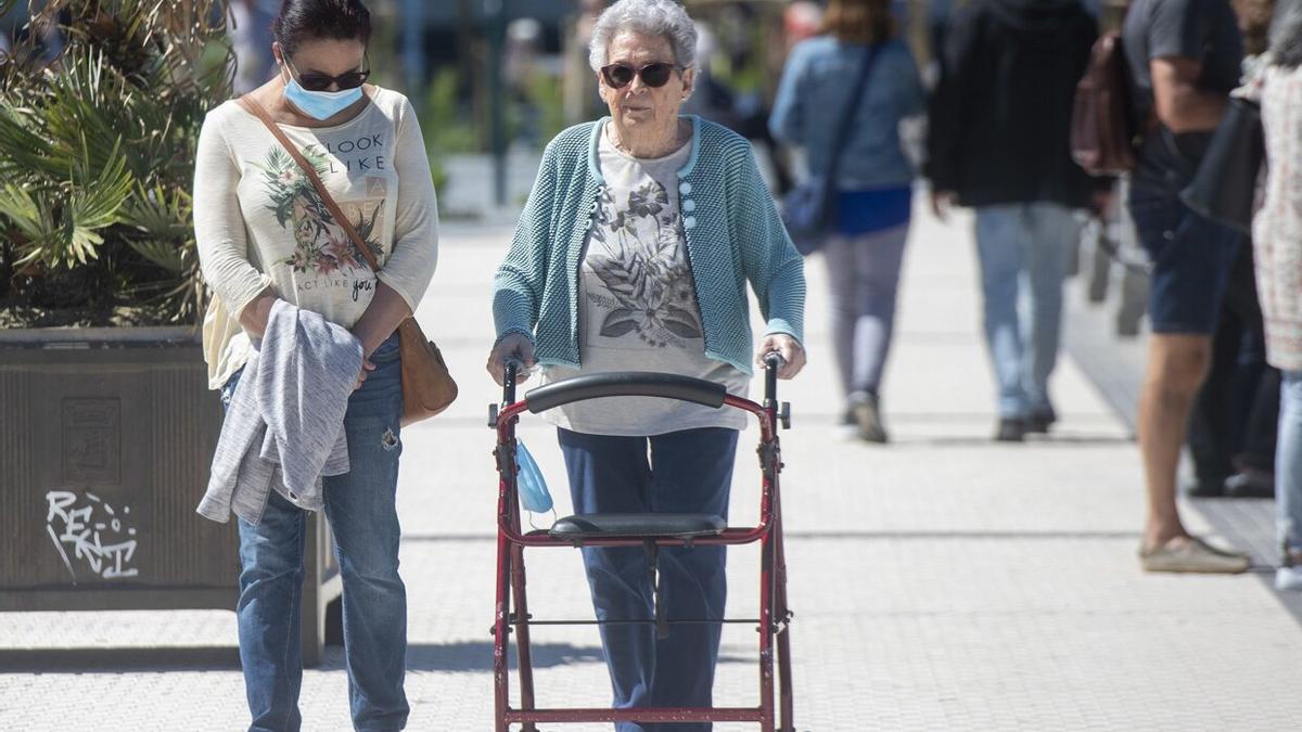 Una persona mayor, junto a la persona que le cuida, pasea por La Concha / Ruben Plaza