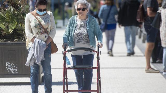 Una persona mayor, junto a la persona que le cuida, pasea por La Concha / Ruben Plaza
