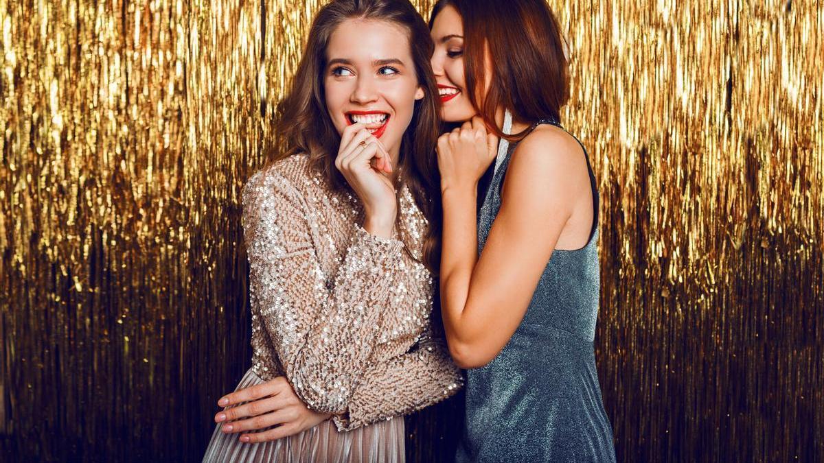 Dos chicas celebrando el nuevo año con vestidos elegantes de lentejuelas
