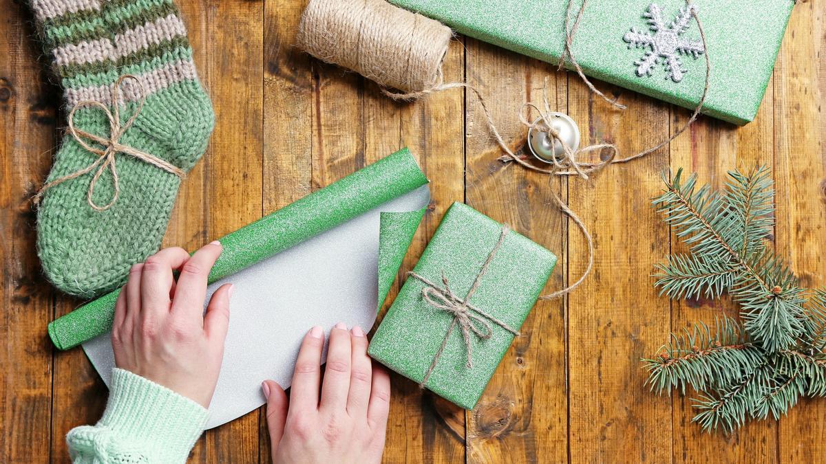 Una mujer envuelve regalos con papel y cuerda de yute.